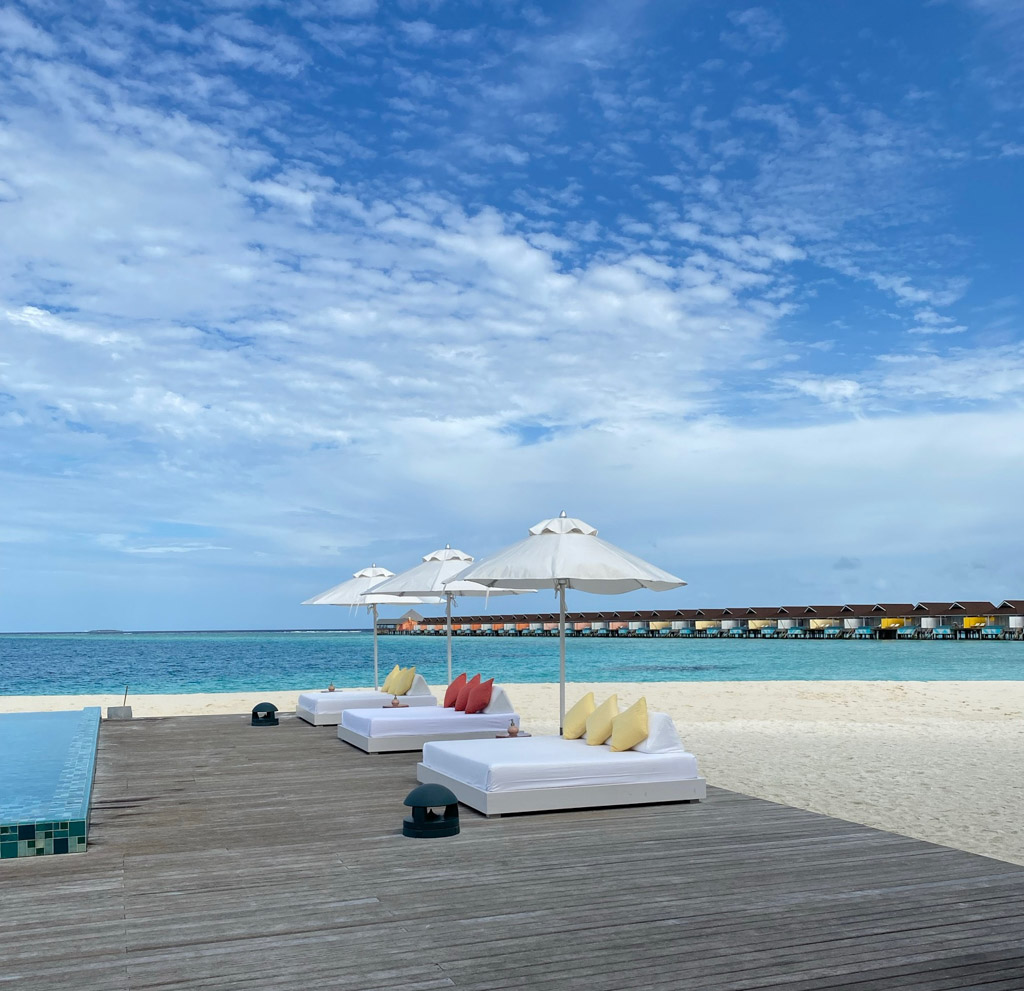 Pool og loungemøbler ved hovedbygningen på The Standard Maldives - vandvillaerne ses i baggrunden